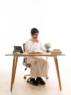 Saudi Student in White Thobe Studying at Desk