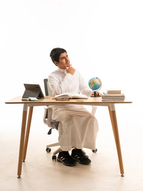 طالب سعودي يفكر خلف مكتب الدراسة