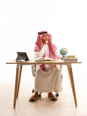 شاب سعودي بالزي التقليدي يفكر أمام مكتبه