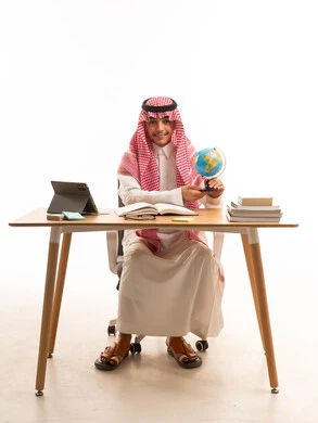 شاب سعودي يحمل مجسم الكرة الأرضية على مكتبه