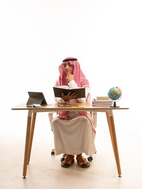 ولد سعودي بالثوب التقليدي يقرأ على المكتب