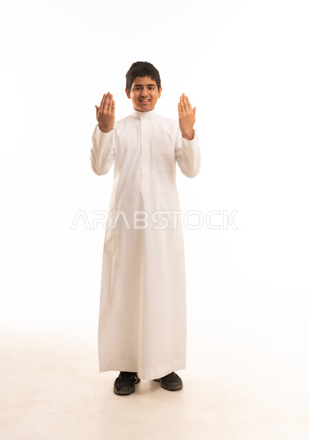 ولد سعودي بالثوب الأبيض يدعو أمام خلفية بيضاء