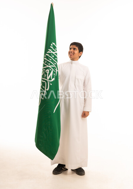 فتى سعودي مع العلم الوطني بالثوب التقليدي