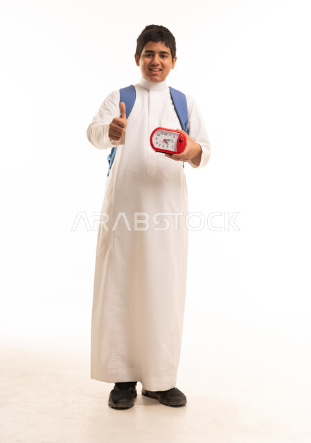 طالب سعودي يحمل ساعة منبه وإشارة الإبهام