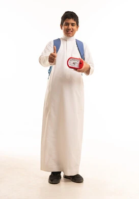 طالب سعودي يحمل ساعة منبه وإشارة الإبهام