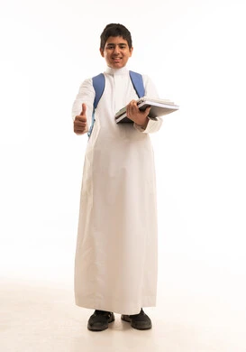 طالب سعودي بالثوب الأبيض يحمل كتباً وإشارة النجاح