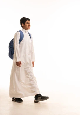 طالب سعودي يمشي بالثوب الأبيض وحقيبة الظهر