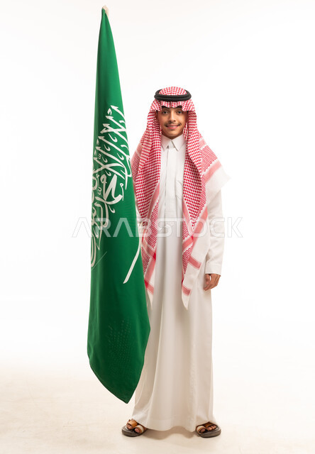 شاب سعودي يحمل علم المملكة العربية السعودية بخلفية بيضاء