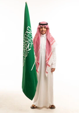 شاب سعودي يحمل علم المملكة العربية السعودية بخلفية بيضاء