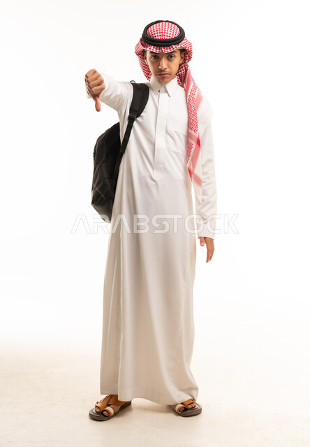 طالب سعودي يرتدي الثوب وحقيبة الظهر يشير بعدم الإعجاب