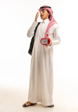 طالب سعودي يحمل حقيبة مدرسية وساعة منبه يتثاءب
