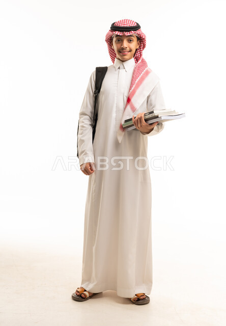 طالب سعودي بالزي التقليدي يحمل كتب دراسية