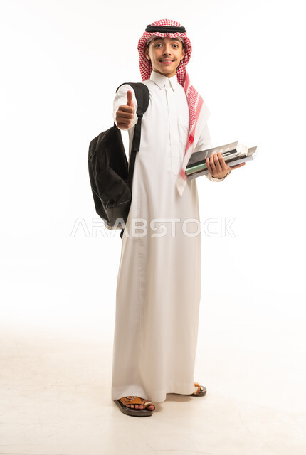 طالب سعودي بالزي التقليدي يحمل كتباً دراسية