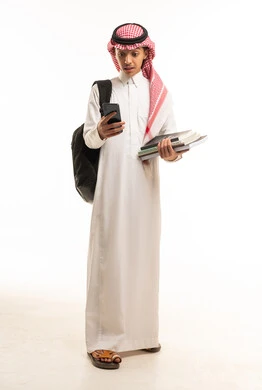 طالب سعودي بالزي التقليدي يحمل كتباً وهاتفاً ذكياً
