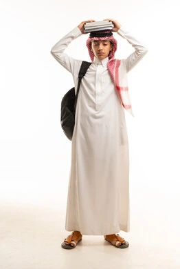 طالب سعودي بالثوب التقليدي يحمل كتب مدرسية