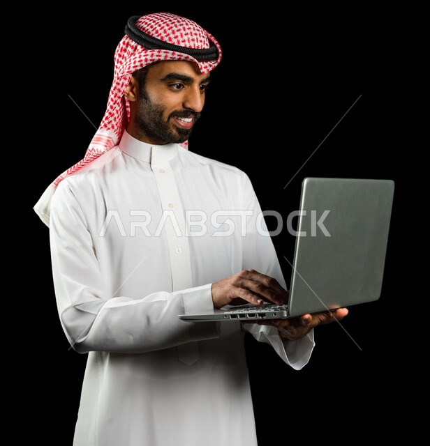 رجل عربي سعودي خليجي يرتدي الزي السعودي، إستخدام جهاز اللابتوب لإنجاز المهام، التسوق الإلكتروني، تطور التكنولوجيا وإستخدام الأجهزة التقنية الحديثة، إجتماع عمل، إدارة الأعمال عن بعد، تصفح الانترنت, إجراء مكالمات فيديو عبر جهاز الحاسوب, خلفيه سوداء