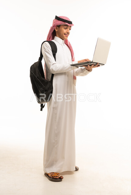 طالب سعودي يحمل جهاز كمبيوتر محمول على خلفية بيضاء
