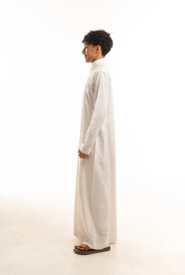 شاب سعودي يرتدي الثوب الأبيض التقليدي بوضعية جانبية