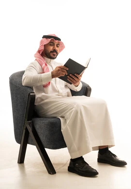 رجل سعودي بالزي التقليدي يقرأ كتاباً في الاستوديو