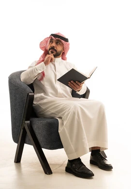 Saudi Man in Traditional Thobe Reading Book in Studio