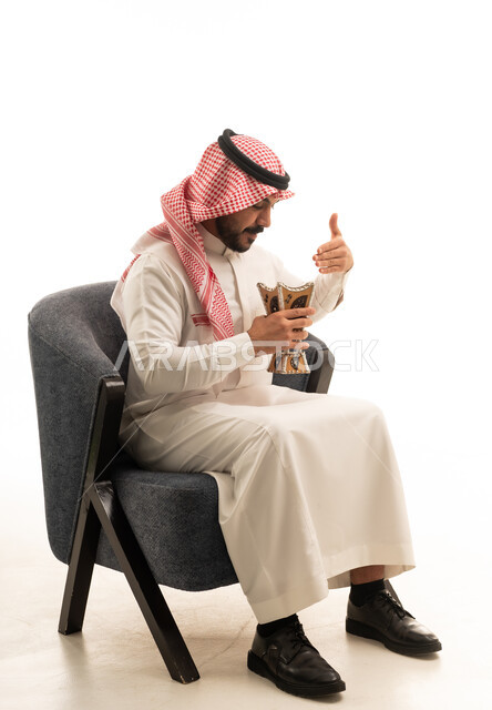 رجل سعودي بالزي التقليدي يمسك مبخرة بخور