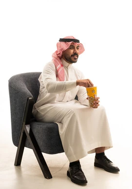 رجل سعودي بالزي التقليدي يتناول الفشار