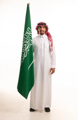 Saudi Man in Traditional Thobe Holding Saudi Flag