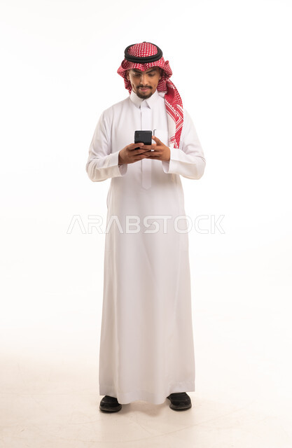 رجل سعودي بالزي التقليدي يستخدم الهاتف الذكي