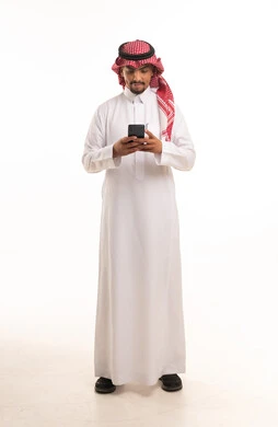 رجل سعودي بالزي التقليدي يستخدم الهاتف الذكي