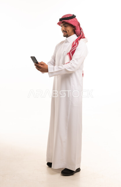 رجل سعودي بالزي التقليدي يستخدم الهاتف الذكي