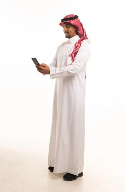 رجل سعودي بالزي التقليدي يستخدم الهاتف الذكي