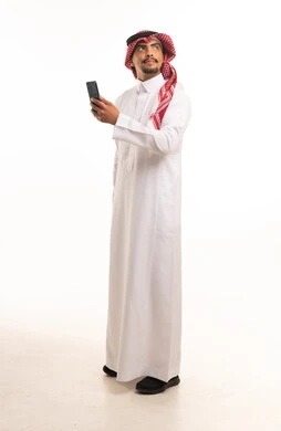 رجل سعودي بالزي التقليدي يمسك هاتف ذكي