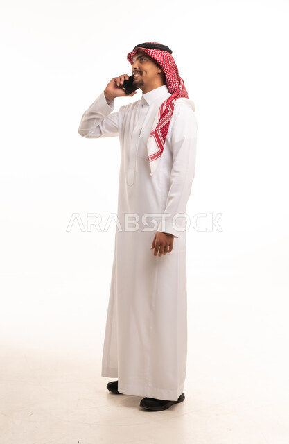 رجل سعودي بالزي التقليدي يتحدث عبر الهاتف الذكي