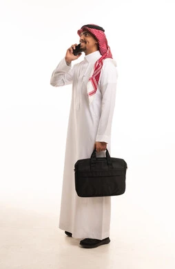 رجل أعمال سعودي يتحدث بالهاتف مع حقيبة عمل