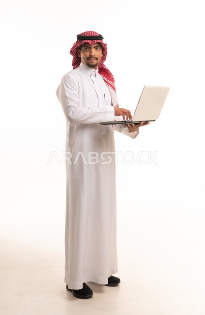 رجل سعودي بالثوب التقليدي يحمل كمبيوتر محمول