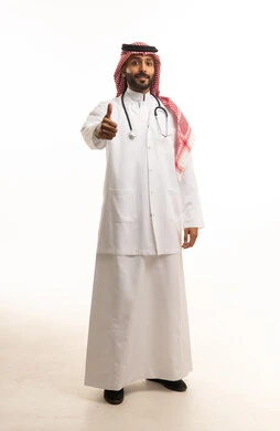طبيب سعودي بالزي الرسمي والمعطف الطبي يشير بالنجاح