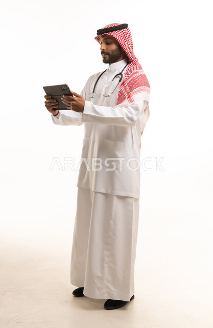 طبيب سعودي يرتدي السماعة الطبية ويستخدم الجهاز اللوحي