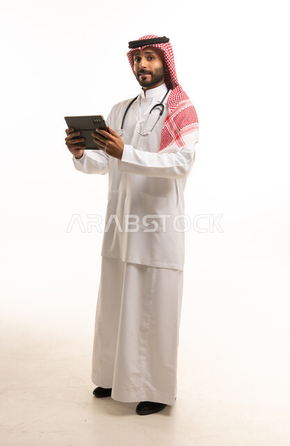 طبيب سعودي يرتدي المعطف الأبيض ويحمل جهاز لوحي رقمي