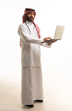 طبيب سعودي يحمل جهاز حاسوب محمول وسماعة طبية