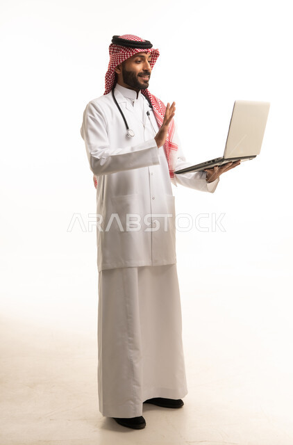 طبيب سعودي يحمل كمبيوتر محمول في استوديو أبيض