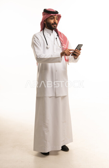 طبيب سعودي يستخدم الهاتف الذكي أمام خلفية بيضاء