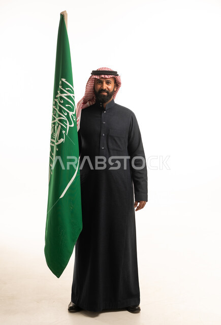 رجل سعودي يمسك علم المملكة العربية السعودية في استوديو