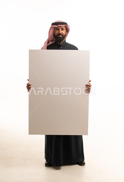 رجل سعودي يحمل لوحة بيضاء فارغة في الاستوديو