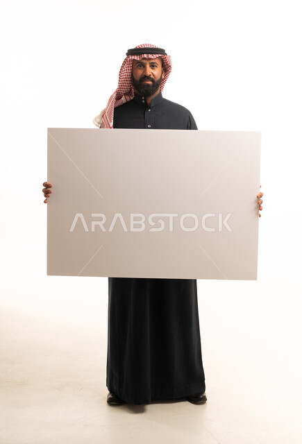 رجل سعودي يمسك لوحة بيضاء فارغة في الاستوديو