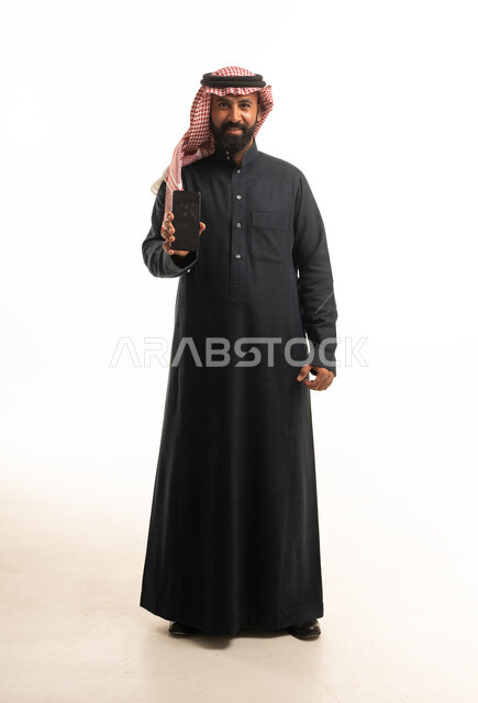 رجل سعودي بالثوب التقليدي يحمل هاتف ذكي
