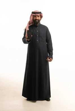 رجل سعودي بالثوب التقليدي يحمل هاتف ذكي