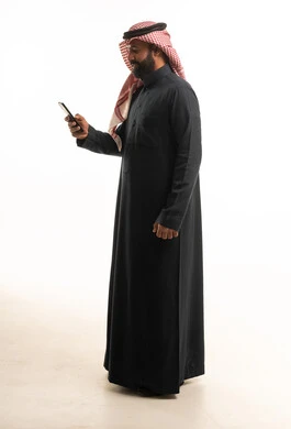 رجل سعودي بالثوب الأسود يستخدم الهاتف الذكي