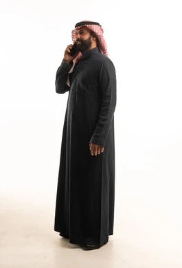 رجل سعودي بالثوب الأسود يتحدث بالهاتف الذكي