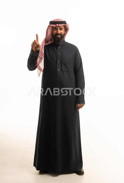 رجل سعودي بالزي التقليدي يشير بإصبعه للأعلى