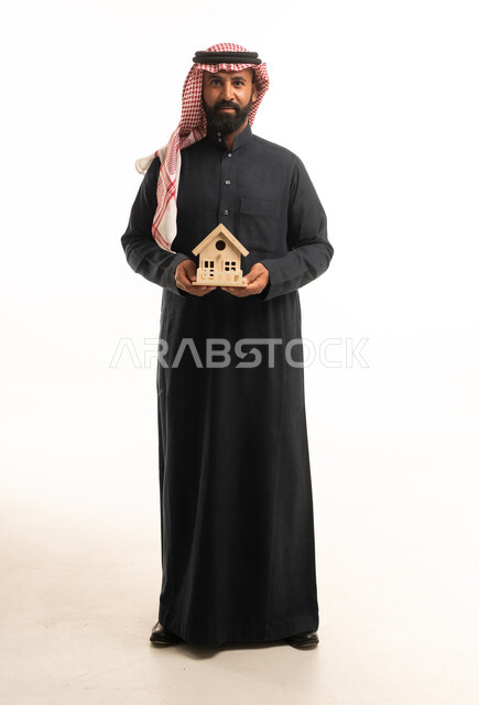 رجل سعودي يمسك بمجسم منزل للتسويق العقاري